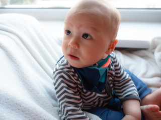 Cute handsome 6 months old mixed half race East Asian Caucasian boy looking happy at the camera,...