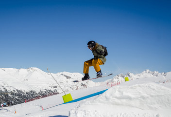 Fototapeta na wymiar Jumping snowboarder with a blue and sunny sky in Zermatt, the swiss Alps
