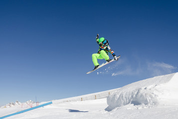 Naklejka na ściany i meble Jumping snowboarder with a blue and sunny sky in Zermatt, the swiss Alps