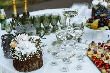 Festive aperitif outdoors. A pyramid of glasses of champagne and also different snacks and fruits at a wedding party