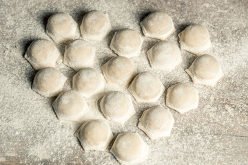 Uzbek national food Chuchvara, like dumplings, lie in the shape of a heart, on a wooden board, in flour