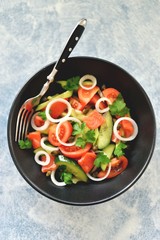 Healthy salad of cherry tomatoes, cucumber, celery, onions, capers and parsley with salted salmon.