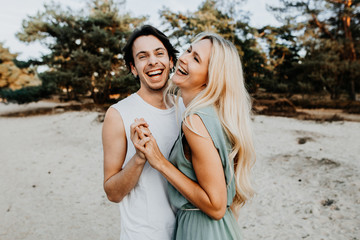 Junges lachendes glückliches Paar hat Spaß in der Natur mit Sand im Hintergrund