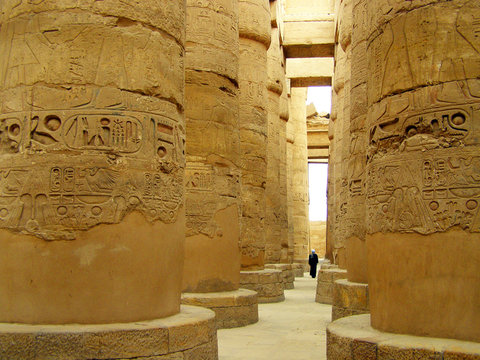 Columns of the Great Hypostyle Hall in the Temple of Karnak, Luxor, Egypt and the man with his back in traditional clothes.