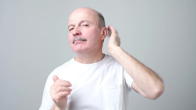 Senior bald funny man straightens hair