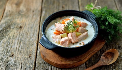 Finnish wild salmon soup with cream on an old wooden background. Rustic style.
