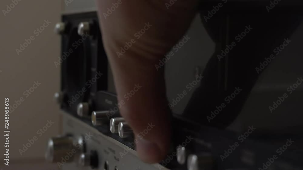 Poster pushing buttons and twisting knobs on an old amplifier.