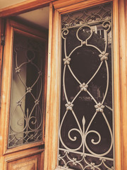Reflection of a building on the street in a glass wooden door with an iron decorative ornament. Old Tbilisi architecture