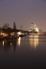 AMSTERDAM, NETHERLANDS - NOVEMBER 21, 2018: Illuminated buildings reflected in calm water, amazing cityscape with boat on Amstel canal at night