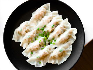 Close up fresh boiled gyoza dumplings with hot steams, Asian dumplings Gyozas potstickers fried over black plate, cooking gyoza dumplings, potstickers, Japanese food.