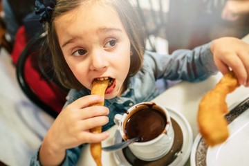 Kid eating churros and chocolate