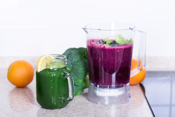 Berries smoothie in blender cup and green kale detox cocktai