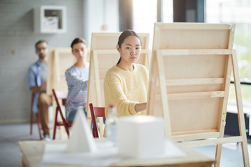 Row of young students painting geometric objects while working individually at lesson