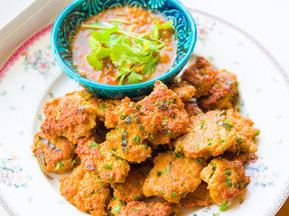 Deep fried fish pasty, Thai fish cake garnished with deep fried basil leaves serves with pickles which are cucumber slices