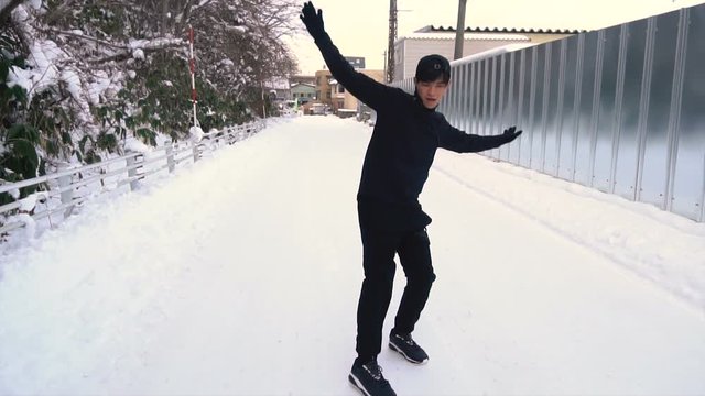 Young Asian Man Sliding on Slippery Icy Road in Winter