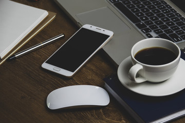 Top view table office with notebook, laptop, mobile, coffee cup, and pen with copy space on wooden table. Business concept.