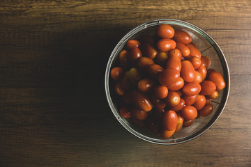 Tamatoes in white cup on wooden table.