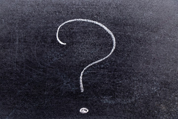 White chalk hand drawing in question mark shape on black board background
