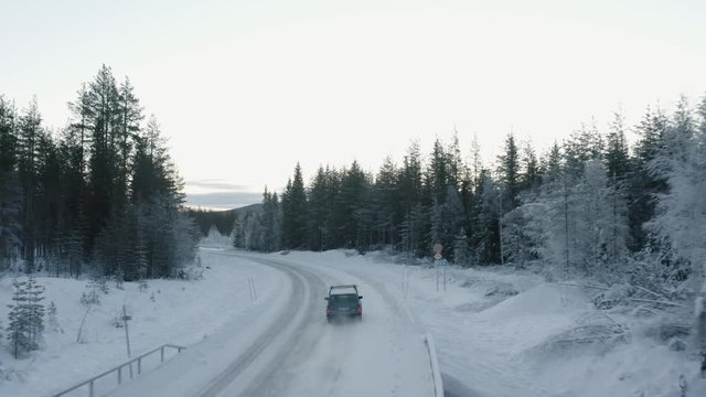 Aerial view of old car driving through the cold Swedish countryside.