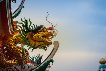 Beautiful statue of Chinese dragon on a roof top in Chinese temple under blue sky background.