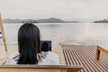 Woman work on her laptop and admire the beautiful lake.