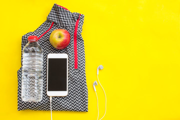 Sport equipment and clothes with mobile phone on yellow background. Top view