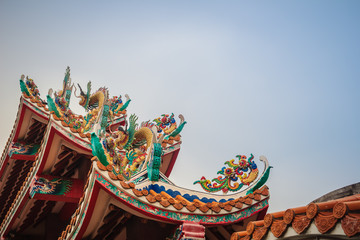 Beautiful large grimace dragons crawling on the decorative tile roof in Chinese temples. Colorful...