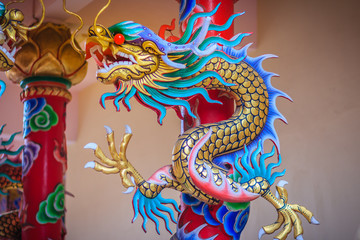 Colorful statue of Chinese dragon wrapped around red pillar. Beautiful statue of dragon carved around temple pole in Chinese public temple.