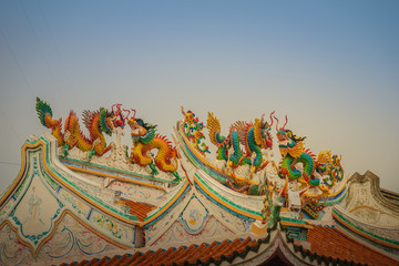 Beautiful large grimace dragons crawling on the decorative tile roof in Chinese temples. Colorful...