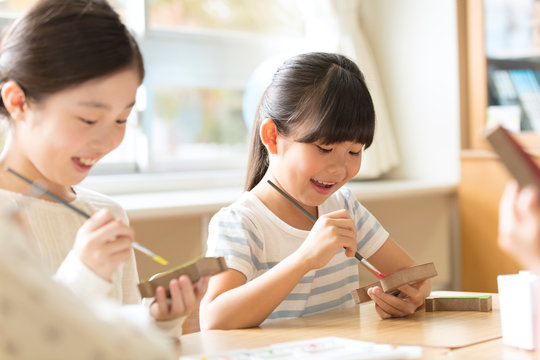 絵具の筆で色を塗る女の子の横顔