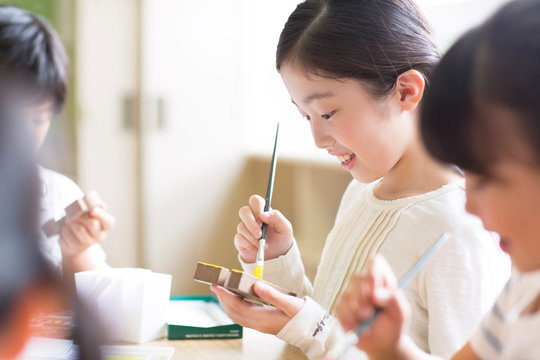 絵具の筆で色を塗る女の子の横顔
