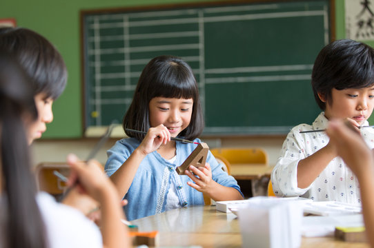 絵具の筆で色を塗る子供たち
