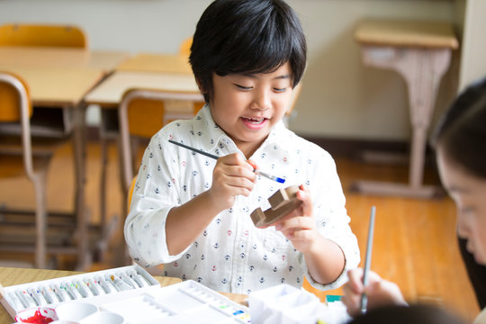 絵具の筆で色を塗る男の子