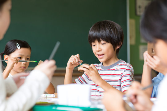 絵具の筆で色を塗る子供たち