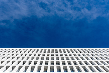 modern tertiary and businness building with white facade and windows that reflect the blue sky