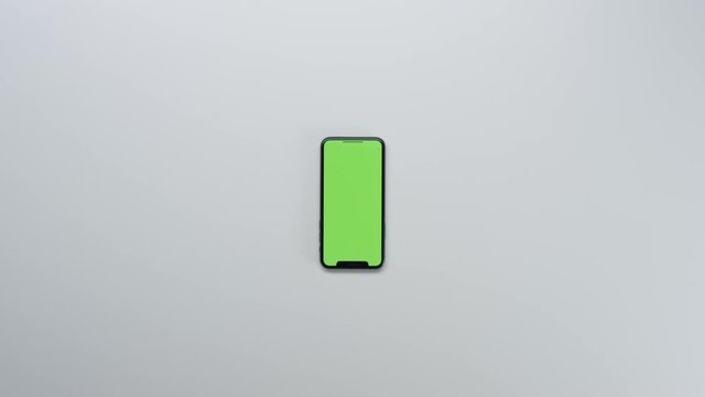 Male hands using smart device with green screen chroma on white clean minimalistic table with top view