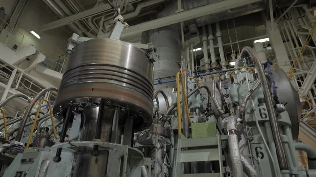New piston head near large marine diesel in engine room of ship
