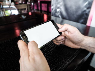 Mockup image of man hand holding mobile phone with blank white screen in vintage cafe, modern restaurant.