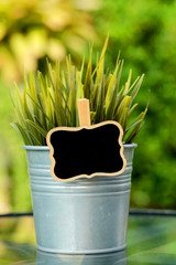 Artificial decorative tree in aluminum pot on wood table in a garden and space for write wording,...