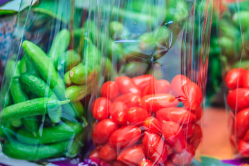 Fresh Sweet Cherry Tomatoes (Solanum lycopersicum L. var. cerasiforme ) and Organic Holland cucumbers are packed in plastic bags for sale at the fresh market in Bangkok, Thailand.