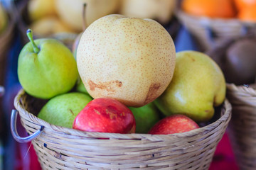 Organic jumbo size of Chinese pears and red apples are mixed in the basket for sale at the fruit market.