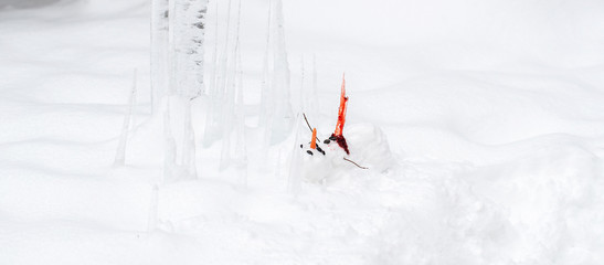 Bloody dead snowman impaled on a sharp icicle during a winter storm