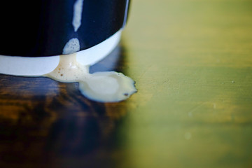 A black Paper coffee mug 16 oz. placed on a wooden table and coffee drip on table.