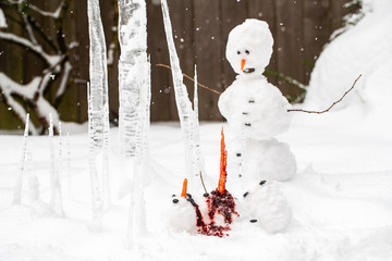 Bloody dead snowman impaled on a sharp icicle during a winter storm