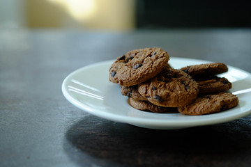 Close up Chocolate cookies in white dish on dark wooden table.