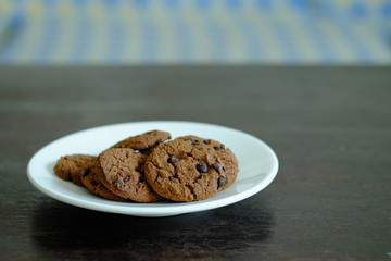Close up Chocolate cookies in white dish on dark wooden table.
