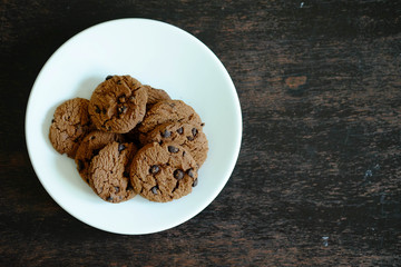 Close up Chocolate cookies in white dish on dark wooden table.