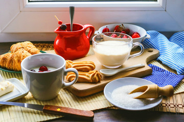 fresh breakfast foods. milk yogurt, croissants and frozen berries.