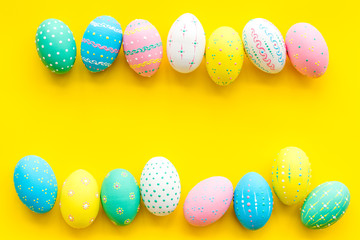 Easter composition. Decorated pastel Easter eggs on yellow background copy space border