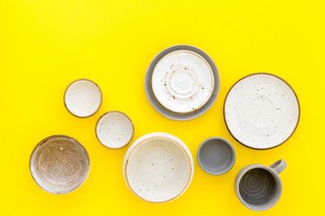 Ceramic tableware pattern. Empty plates and mugs on yellow background top view copy space